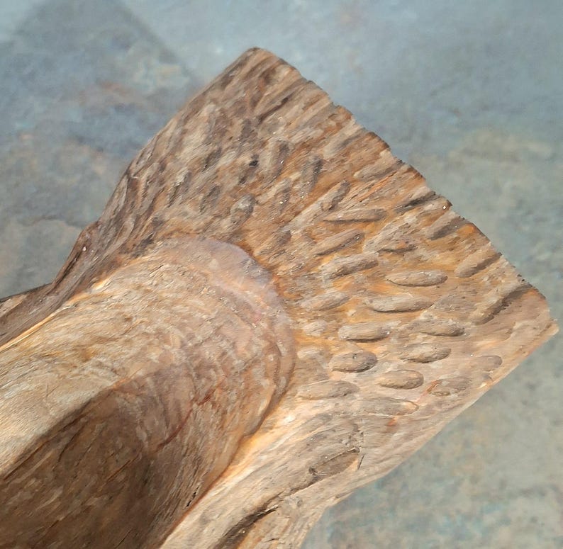 Pu&ograve; includere: Primo piano di una scultura in legno intagliata a mano. La scultura ha una superficie ruvida e strutturata con un motivo a venature naturali del legno. Il legno &egrave; di un caldo colore marrone chiaro con accenti pi&ugrave; scuri.