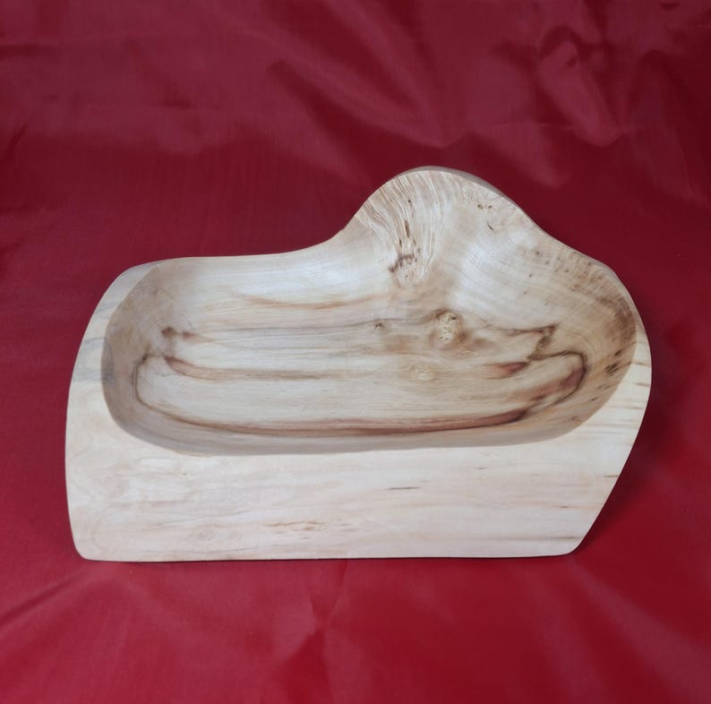 May include: A handcrafted wooden bowl with an unusual, organic form. The bowl is made from light-coloured wood with visible grain patterns and a smooth, polished finish. The bowl's dimensions are approximately 30 cm long, 20 cm wide, and 8 cm deep.