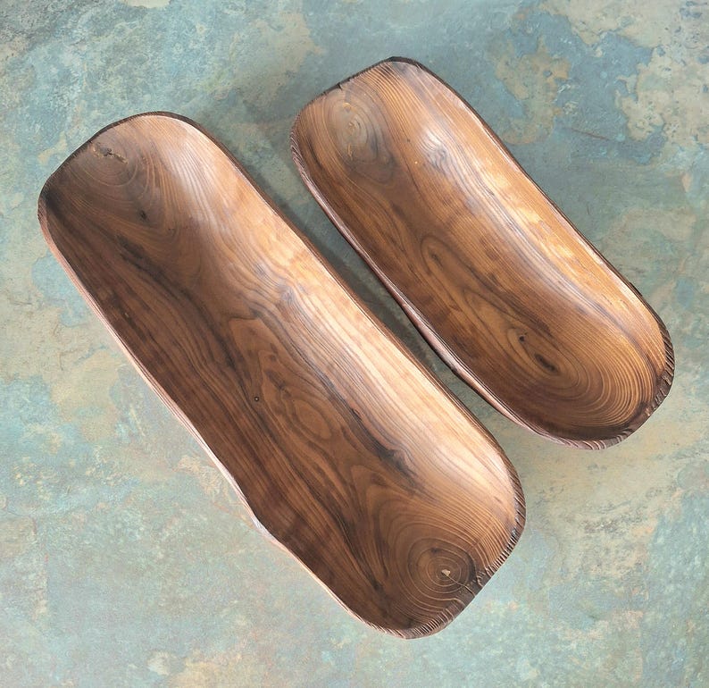 May include: Two wooden, rectangular bowls with a natural wood grain pattern. The bowls are a warm brown color and have a smooth, polished finish. The bowls are empty and appear to be handmade.