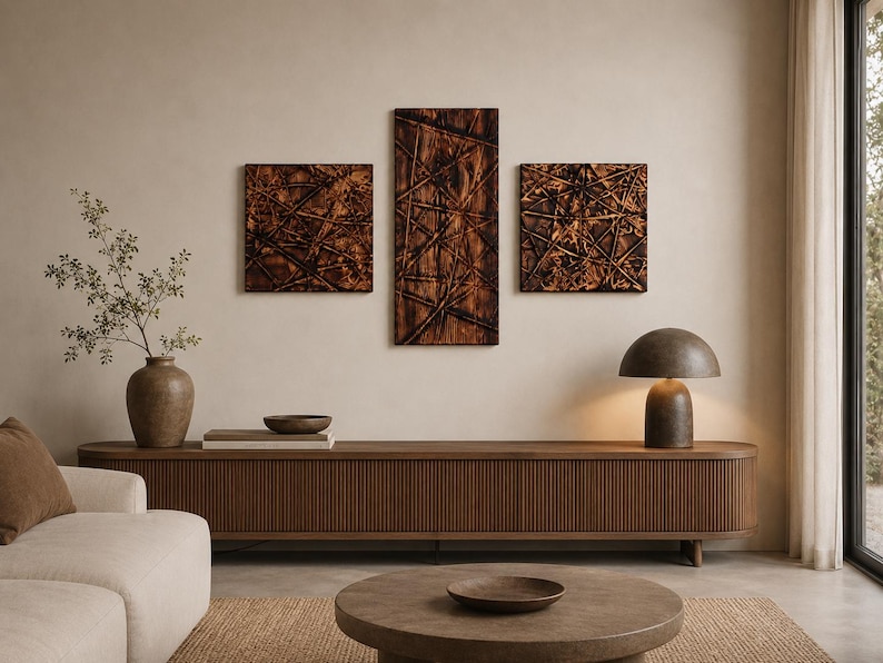 May include: A living room scene with a wooden console table, a round coffee table, and a cream sofa. Three abstract wooden wall art pieces hang above the console. A brown lamp and a vase with greenery complete the decor.