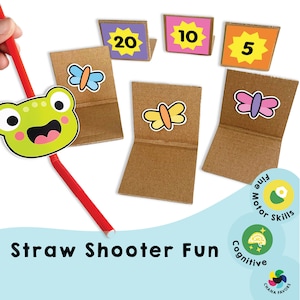 May include: A straw shooter game with a frog head, three cardboard targets with butterflies and numbers 5, 10, and 20, and a red straw. The game is designed to build fine motor skills and cognitive skills.
