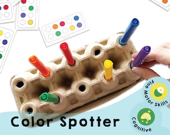 Pode incluir: Um carton de ovos de cartão com marcadores coloridos inseridos nas ranhuras. O carton está etiquetado como "Color Spotter" e tem um fundo azul. A imagem também inclui três círculos com texto: "Fine Motor Skills", "Cognitive" e "Chana Favors".