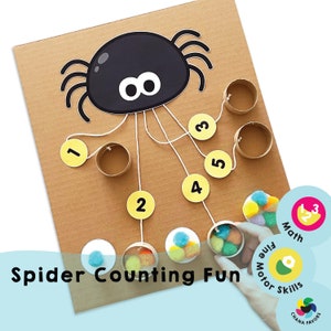 Puede incluir: Un tablero de juego de cartón marrón con una araña negra con ojos blancos y ocho patas. La araña tiene cuerdas atadas a ella que conducen a seis círculos amarillos con los números del 1 al 5. El tablero de juego está etiquetado como "Spider Counting Fun" y tiene una pequeña mano sosteniendo un pompón azul y amarillo. El tablero de juego también tiene una etiqueta que dice "Motor Skills" y otra etiqueta que dice "Math".