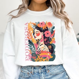 May include: White sweatshirt with a colorful graphic print of a woman with flowers and the word "PODEROSA" in pink lettering.