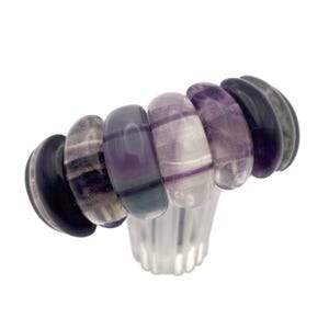 May include: A bracelet composed of six polished, rounded stone beads featuring varying shades of purple, lavender, and deep violet with natural banded patterns. The beads are strung together in a horizontal row, displaying a smooth, glossy finish.