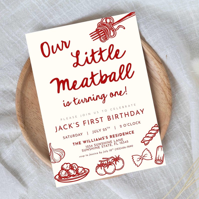 Może przedstawiać: Kremowe zaproszenie z czerwonym tekstem i ilustracjami. Tekst brzmi "Our Little Meatball is turning one!" i ogłasza pierwsze urodziny Jacka. Zawiera ilustracje makaronu i klopsik&oacute;w.