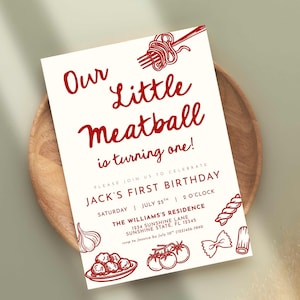 Może przedstawiać: Kremowe zaproszenie z czerwonym tekstem i ilustracjami na pierwsze urodziny. Tekst brzmi "Our Little Meatball is turning one!" ze szczeg&oacute;łami przyjęcia. Zawiera ilustracje z motywem makaronu, w tym spaghetti i klopsiki.