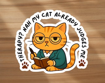 Può includere: Un adesivo con un gatto tabby arancione con occhiali e un blazer verde acqua, che tiene in mano una penna e un libro. Il testo intorno al gatto recita "Terapia? No, il mio gatto mi giudica già" con impronte di zampe.