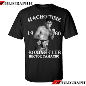 Könnte beinhalten: Schwarzes T-Shirt mit einem weißen Grafikdesign, das einen Boxer in einem Boxring zeigt. Die Grafik enthält den Text "Macho Time 19 86 Boxing Club Hector Camacho".