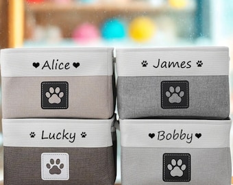 May include: Four fabric storage bins in shades of gray and brown, each with a white top band. Each bin has a name printed on it: Alice, James, Lucky, and Bobby. A paw print design is on each bin.