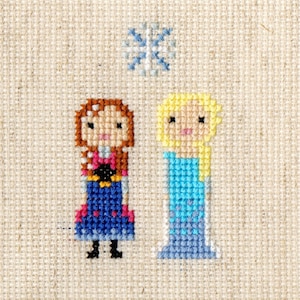 May include: Cross-stitch embroidery of two cartoon girls, one with brown hair and a blue dress, the other with blonde hair and a light blue dress. A snowflake is above them.