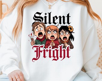 May include: White sweatshirt with a graphic of three cartoon figures with shocked expressions, holding candles. The words "Silent Fright" are printed above and below the figures in a gothic font.
