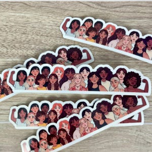 May include: A set of stickers featuring a group of women with different skin tones and hairstyles, all with their arms raised in a gesture of empowerment. The stickers are arranged in a semi-circle shape, with the women's faces looking out at the viewer.
