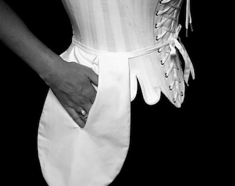 May include: A white corset with a lace-up back and a white pocket on the front. The corset is made of a smooth, silky fabric.