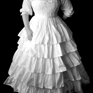 May include: A white, ruffled, floor-length dress with a fitted bodice and a low neckline. The dress has a simple, elegant design and is perfect for a formal occasion.