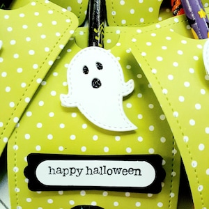 May include: A green and white polka dot treat bag with a white ghost cutout and a black banner that says "happy halloween".
