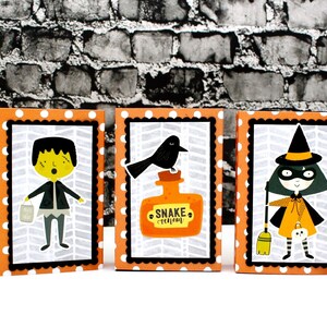 May include: Five Halloween-themed boxes with orange and white polka dot backgrounds. Each box features a different character: a cat, Frankenstein, a crow, a witch, and a pumpkin.