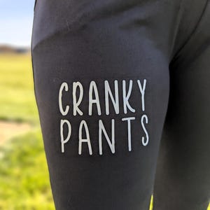 May include: Black leggings with the text "Cranky Pants" printed in white on the left thigh.