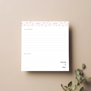 Könnte beinhalten: Weißer Notizblock mit schwarzem Punktmuster oben und gepunktetem Raster unten. Enthält Abschnitte für Aufgaben und Notizen, mit dem Text "Getting it done." in schwarzer Schrift.