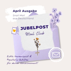 Könnte beinhalten: Ein lila Umschlag mit dem Text "JUBELPOST Mail Club" und "April Ausgabe" in Weiß. Der Umschlag enthält ein weißes Papier mit einem Zweig getrockneter Blumen. Das Design umfasst eine Briefmarke und ein dekoratives Siegel.