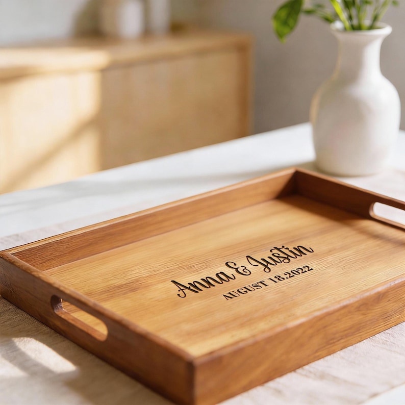 May include: A rectangular wooden serving tray with cut-out handles. The tray is engraved with the names "Anna & Justin" and the date "AUGUST 18.2022". The tray is made of light brown wood.