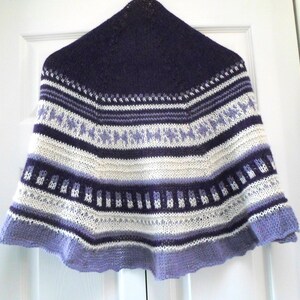 May include: A purple, white, and lavender knitted shawl with a geometric pattern.
