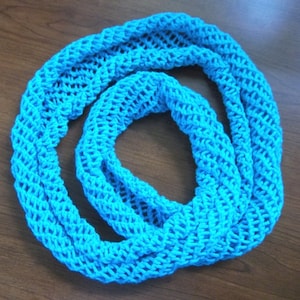 Może przedstawiać: Jasno błękitny, szydełkowy szal typu infinity z luźnym, otwartym splotem.
