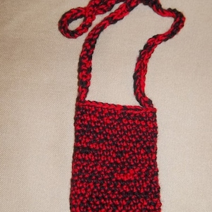 May include: A small red and black crocheted bag with a long strap.