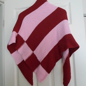 May include: A triangular knitted shawl with alternating stripes of pink and burgundy.
