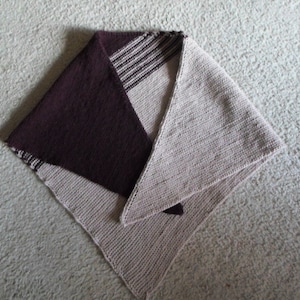May include: A triangular knitted shawl with a brown and white striped section in the center. The shawl is made of a soft, textured yarn.