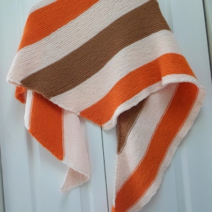 May include: A triangular knitted scarf with stripes of orange, brown, and white.