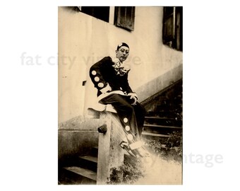 Antique 1930s Photograph of a Harlequin Clown Smoking a Cigarette Sitting on a Railing man glasses costume performer circus vintage