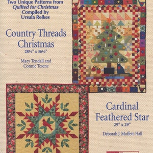 May include: A book cover featuring two quilt patterns: "Country Threads Christmas" and "Cardinal Feathered Star." The Christmas quilt has a tree design. The other quilt has a star design with a cardinal. The book is from "That Patchwork Place."