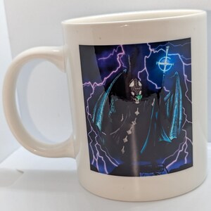 May include: White ceramic coffee mug with a black and blue image of a figure with wings and a halo, standing in front of a background of purple lightning bolts.