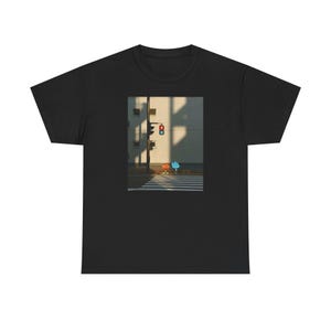 Può includere: T-shirt nero con una stampa grafica di una scena di strada. Il design include un attraversamento pedonale, un semaforo e due personaggi dei cartoni animati. La scena è ambientata contro un edificio con ombre.