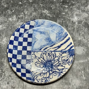 May include: A white ceramic plate with a blue and white checkered pattern, a blue and white butterfly design, and a blue and white floral design.