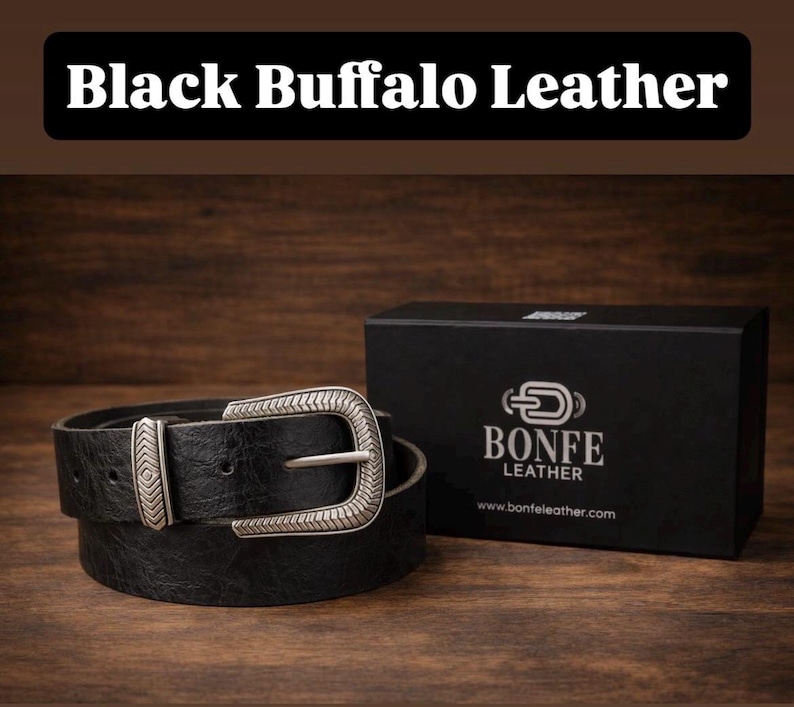 a black buffalo leather belt and its packaging box, both placed on a wooden surface.