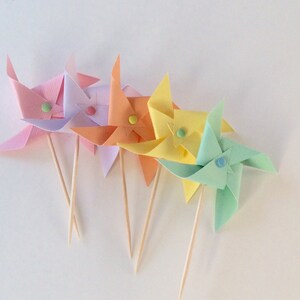 May include: Five pastel colored paper pinwheels with wooden sticks. The pinwheels are pink, purple, orange, yellow, and light blue.