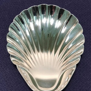 May include: A silver shell-shaped dish with a smooth, reflective surface.