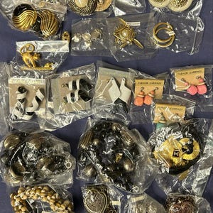 Könnte beinhalten: Eine Auswahl an Schmuck in verschiedenen Stilen und Farben, darunter Ohrringe, Armbänder und Halsketten. Der Schmuck ist in durchsichtigen Plastiktüten verpackt, die mit den Etiketten "Fashion Earrings" und "Made in Korea" versehen sind.