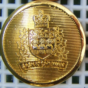 May include: A gold-coloured button with a crest featuring a crown and a shield with three lions. The text "SASKATCHEWAN" is inscribed below the crest.