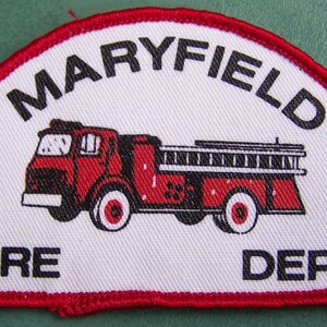 May include: A white patch with a red border, depicting a red fire truck with black details. The text "MARYFIELD FIRE DEPT." is printed in black.
