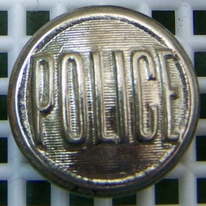May include: A silver metal button with the word "POLICE" embossed on it.