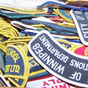 Könnte beinhalten: Eine Sammlung bunter gestickter Aufnäher mit verschiedenen Designs und Texten, darunter "CITY OF OPERATIONS", "WINNIPEG DEPARTMENT" und "YORK SCHOOL LTD".