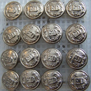 Op de afbeelding: Een verzameling van 15 zilverkleurige metalen knopen met de letters "FD" in een kransontwerp.