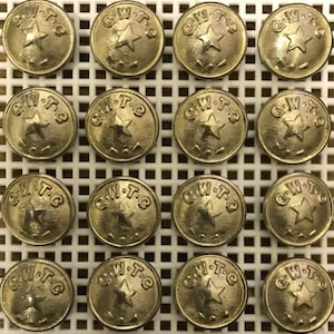 Puede incluir: Una colección de 16 botones de metal de color dorado, cada uno con una estrella y el texto "C.W.T.C.".