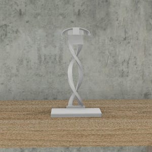 May include: A white, twisted, metal stand with a square base. The stand is designed to hold a small object, such as a phone or a candle.