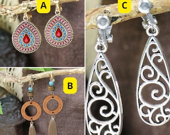 May include: Three pairs of dangle earrings with clip-on backs. The first pair features a teardrop-shaped design with red, blue, and pink enamel. The second pair features a teardrop-shaped design with a wood circle and a brown tassel. The third pair features a teardrop-shaped design with a silver filigree pattern.