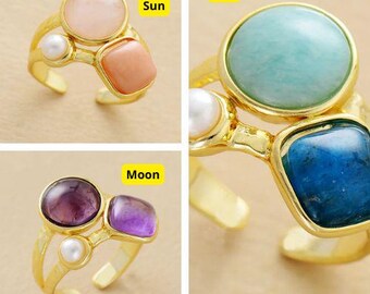 Könnte beinhalten: Vier goldene Ringe mit verschiedenen farbigen Steinen. Die Ringe sind mit "Sonne", "Stern", "Mond" beschriftet, und jeder Ring hat eine andere Kombination von Steinen.