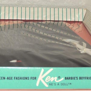 Puede incluir: Un conjunto de moda vintage de muñeca Ken de Mattel en su caja original. La caja es de color turquesa y blanco con el texto "Teen-Age Fashions for Ken, Barbie's Boyfriend, He's a Doll". El contenido está envuelto en plástico.